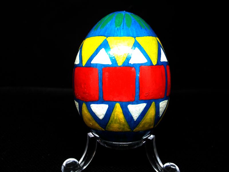 Blaugrundiertes Ei mit roten Quadraten und gelben Dreiecken