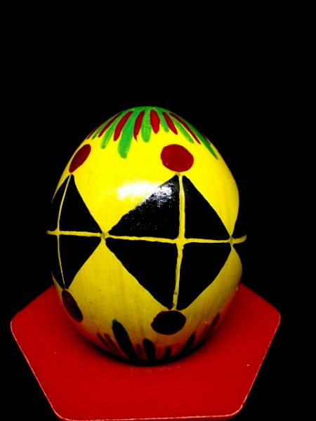 gelb grundiertes Ei mit schwarzen Dreiecken zum Quadrat mit roten Punkten und gelben Strichen